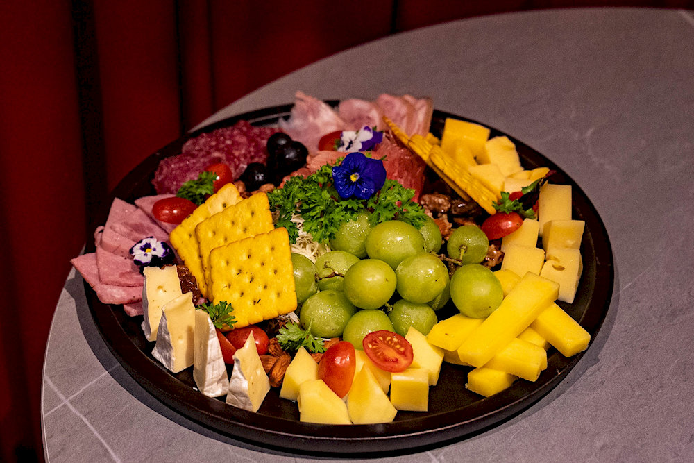 A refined appetizer platter at SkyOn9, beautifully arranged with premium cheeses, imported cold cuts, fresh fruits, and crispy crackers